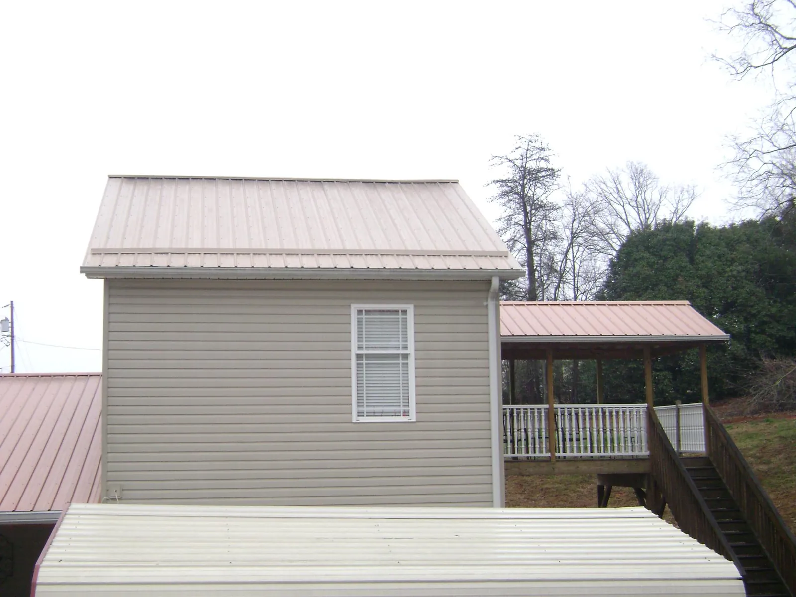 Tan metal roofs on a two story addition and attached porch, from a Roof Replacement job in Willow City